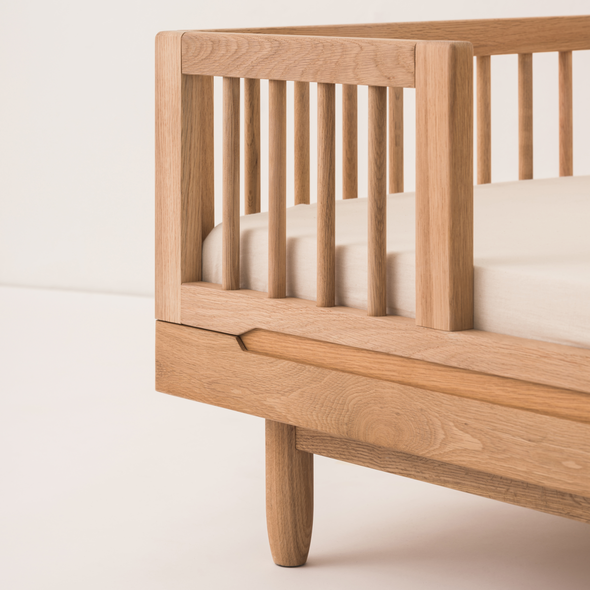 Wooden crib with a white mattress on a light background