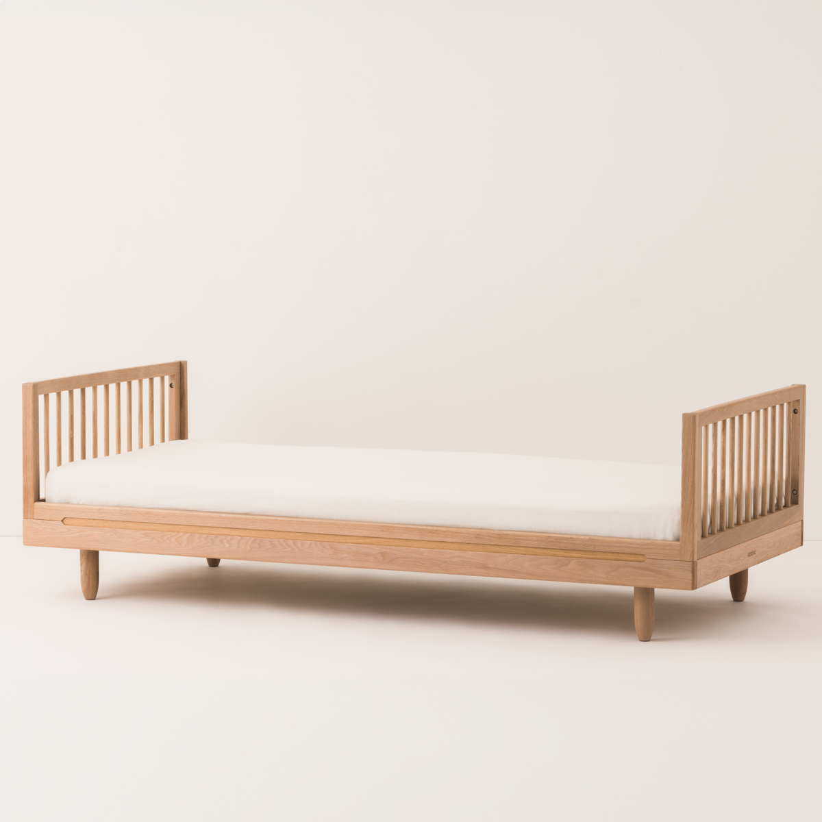 Wooden bed with white mattress on a plain background