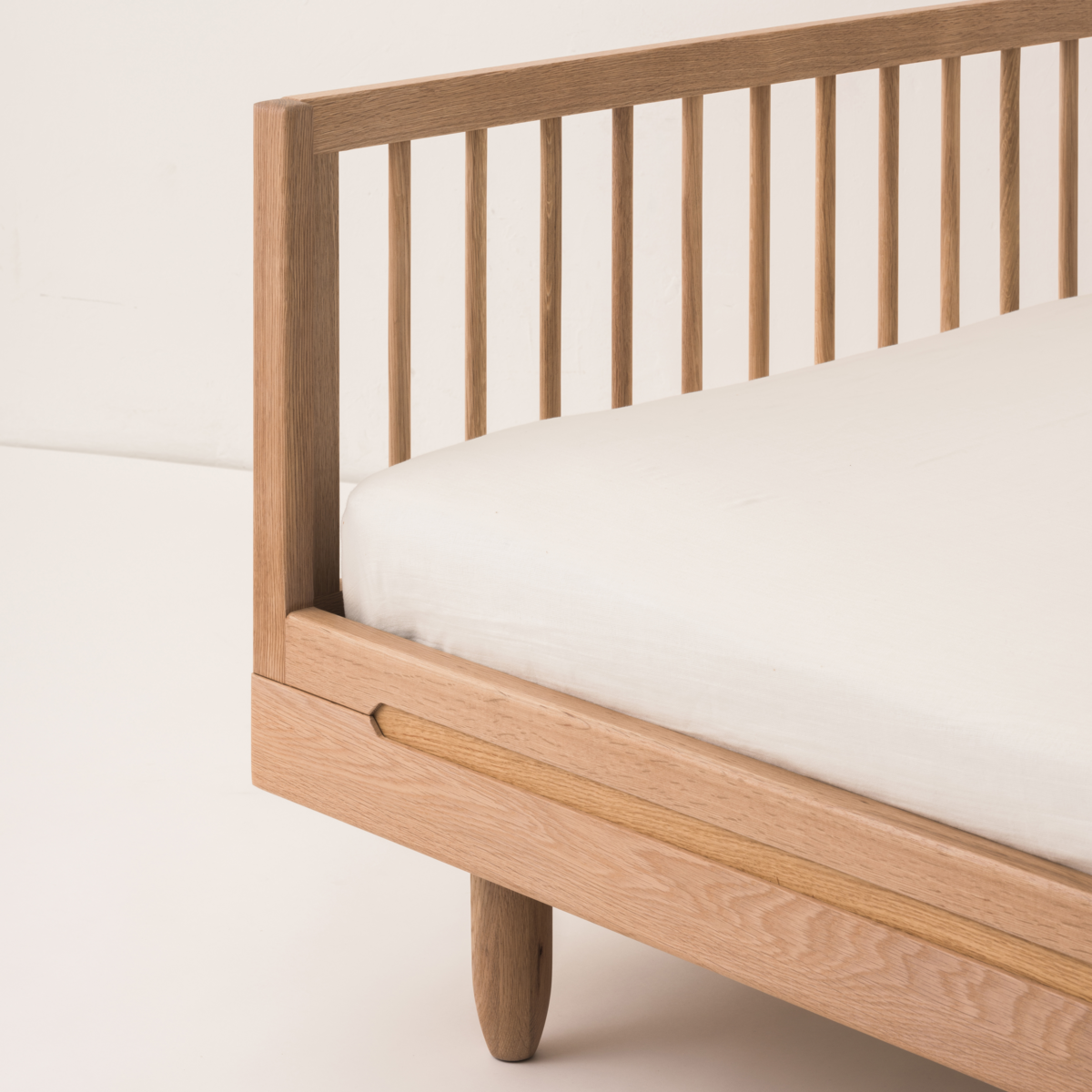 Wooden bed frame with a white mattress on a light background